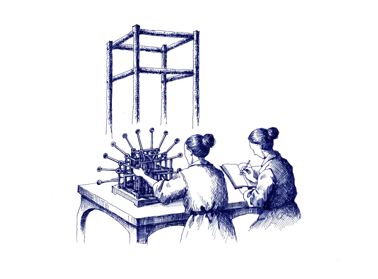 Two figures seen from behind stand at a workbench, where the tester pulls one of many levers on a working scale model of a machine and the designer beside writes in an open notebook, while beyond the bench the full-size machine stands as a tall bare unbuilt frame.