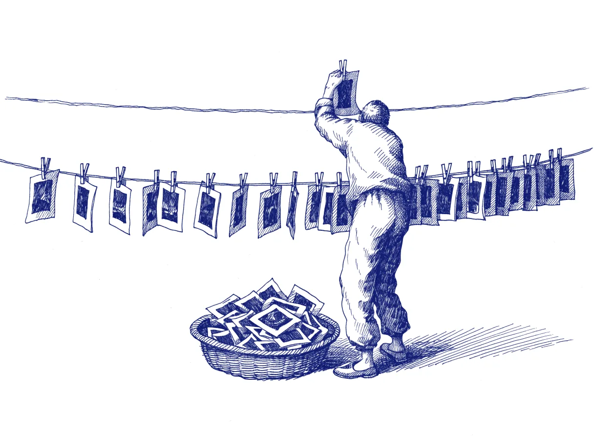 A long wire hung with dozens of photographic prints on pegs, where a figure seen from behind lifts off a single print while a basket below fills with the discarded rest, the whole scene drawn with wide empty margins on every side.